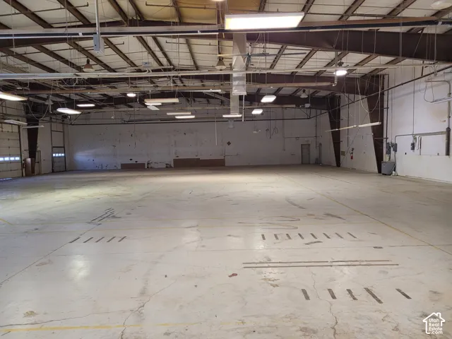 Spacious commercial interior with high ceilings, multiple roll-up doors, and exposed structural beams
