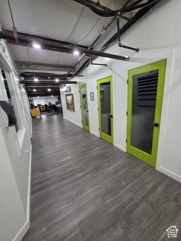Hallway featuring wood-finish flooring, white walls, and bright green doors with glass panels