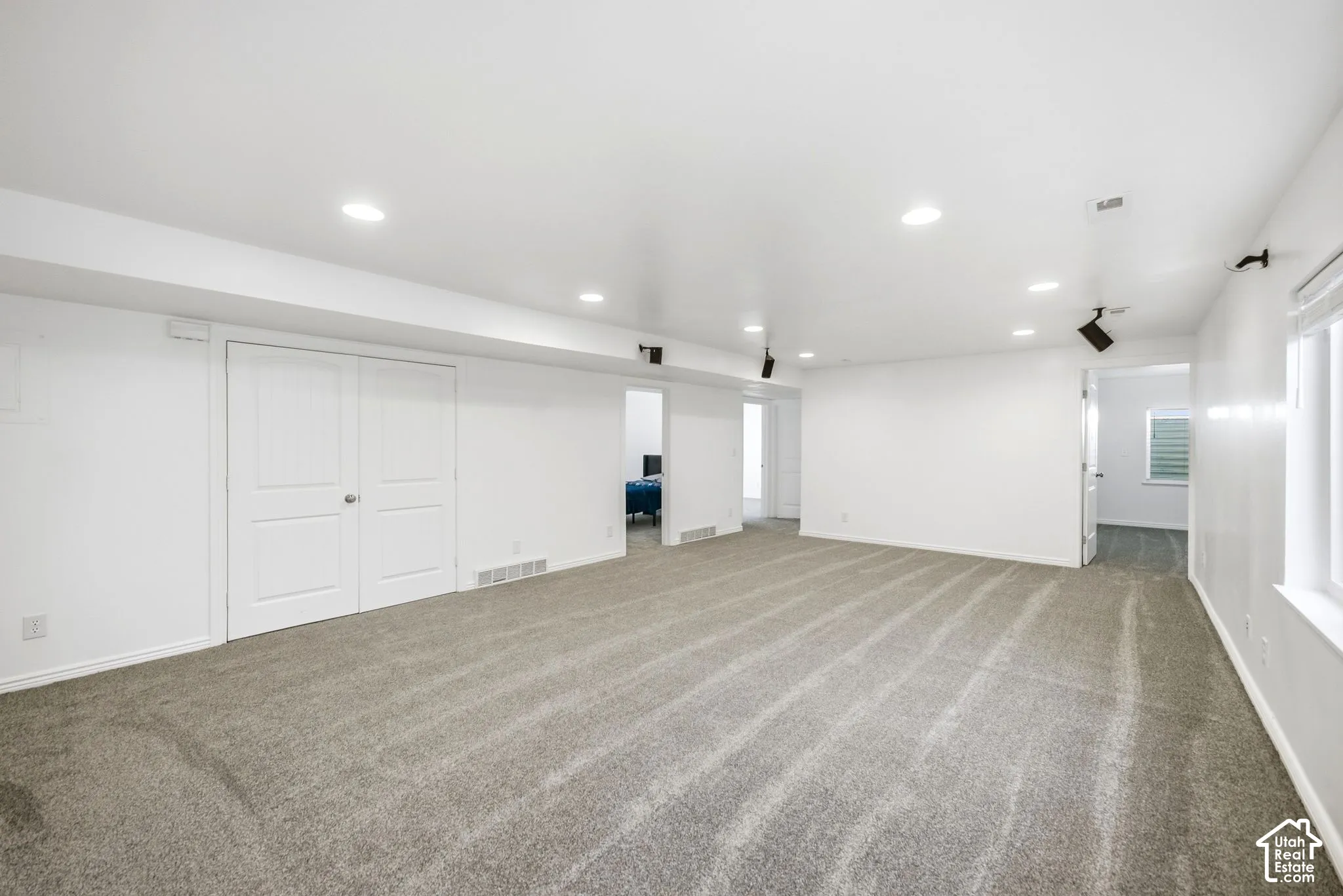 Spacious room with recessed lighting, light gray carpeting, white walls, and white bi-fold doors