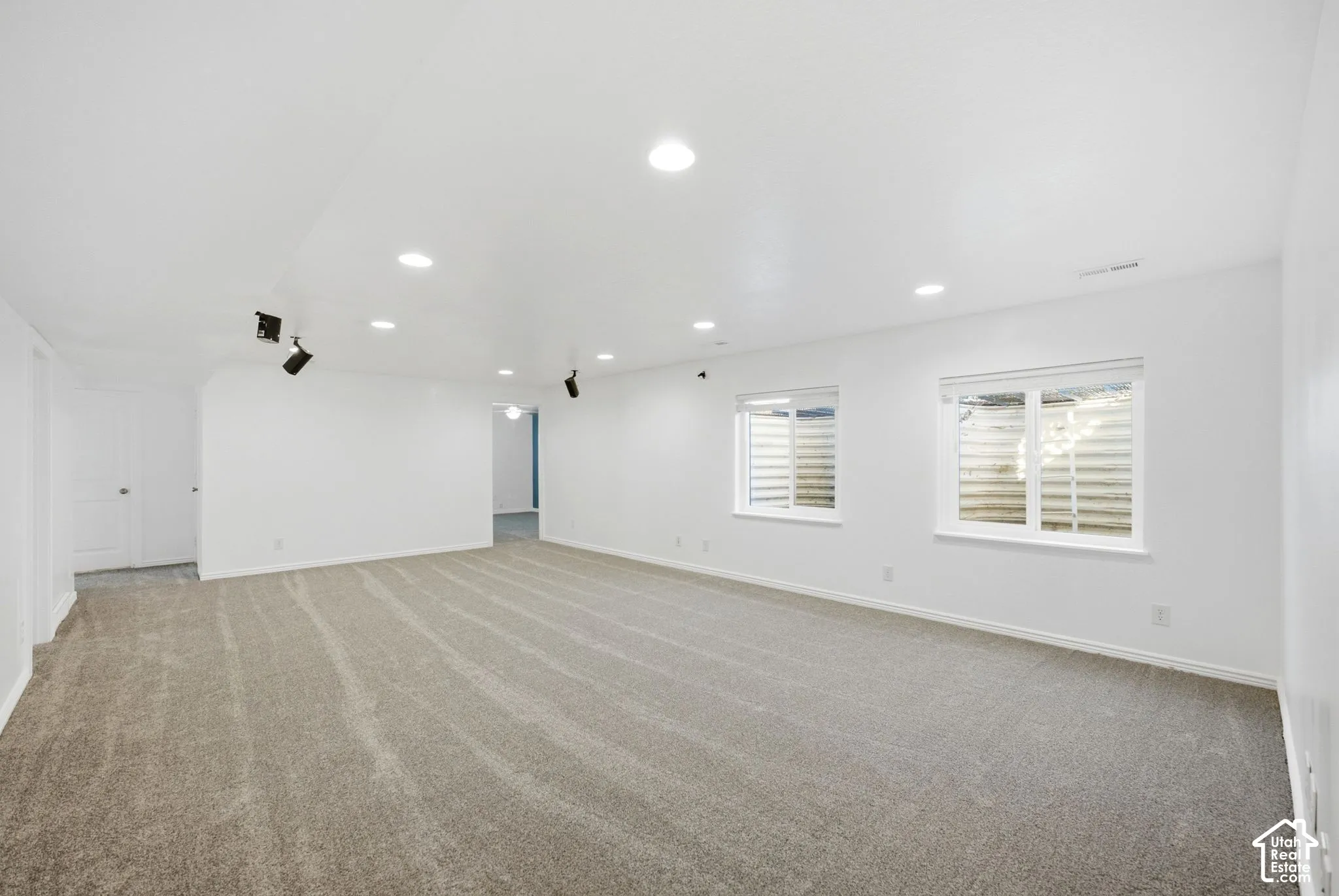 Spacious interior with neutral carpeting, recessed lighting, track lighting, and multiple windows