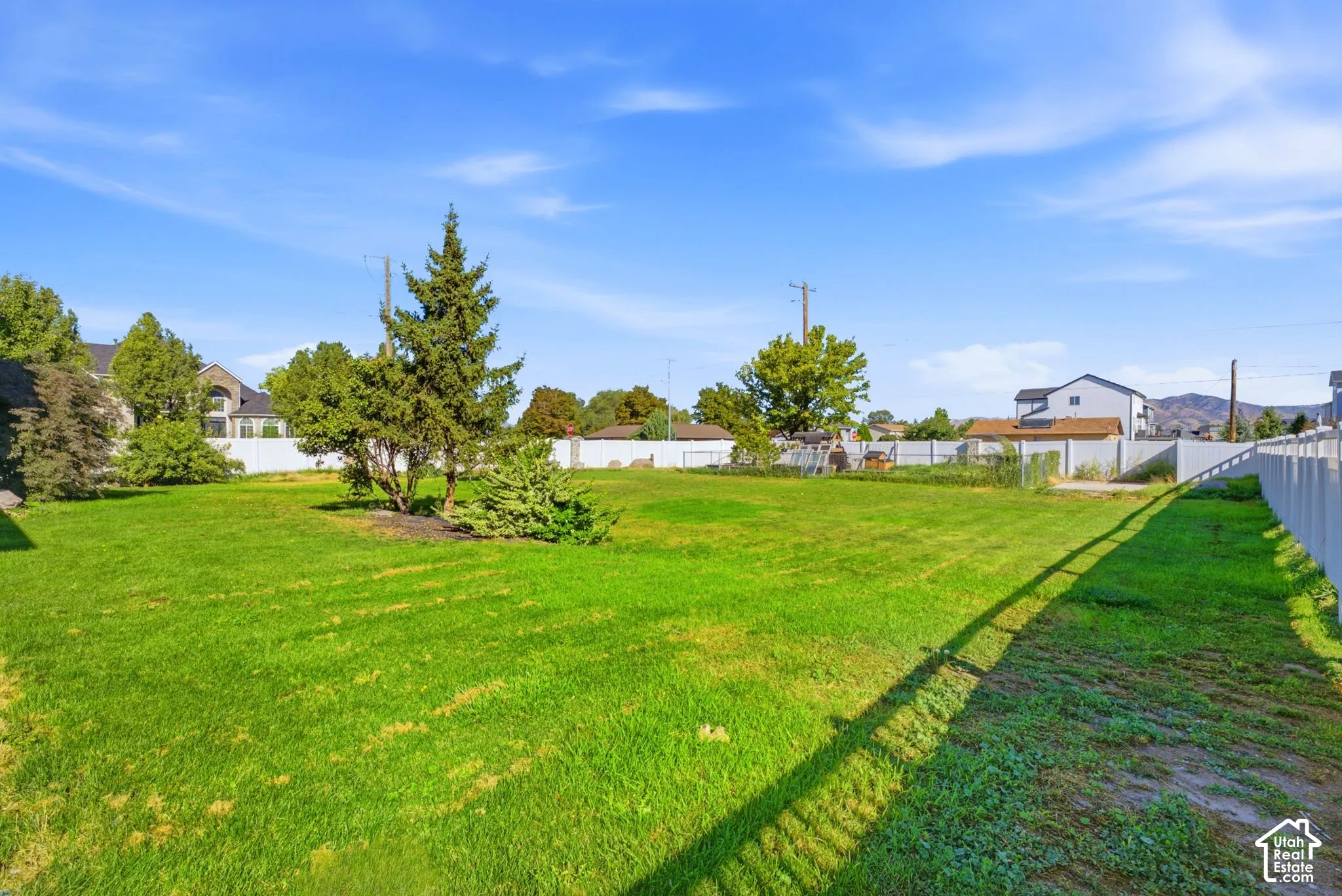 Expansive green space with natural landscaping, mature trees, and perimeter fencing