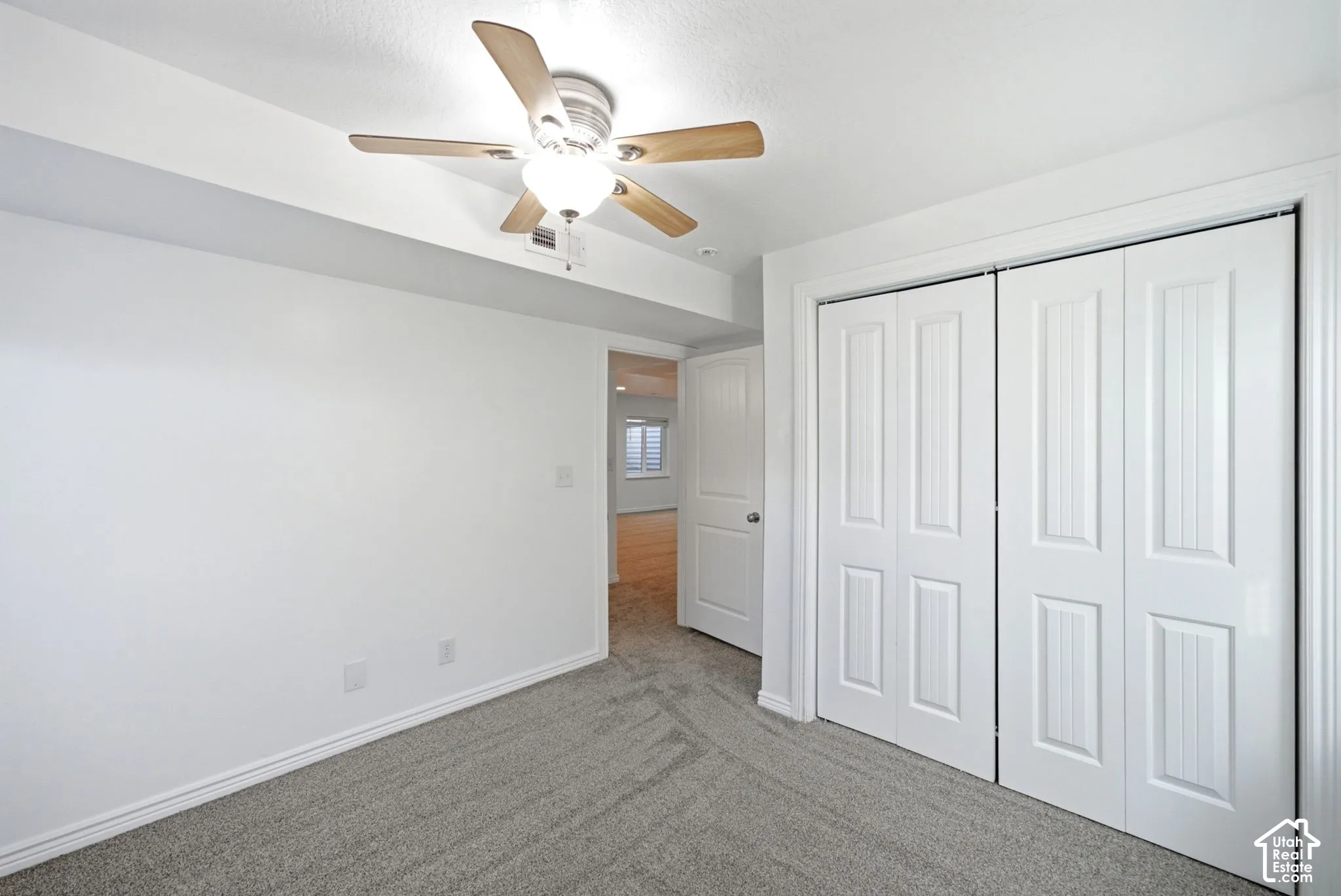 Wall-to-wall carpeting, ceiling fan with light fixture, and bifold closet doors