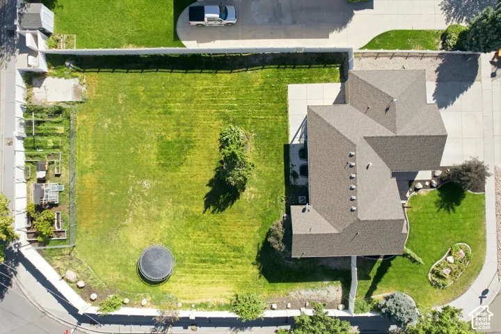 Expansive green lawn, mature trees, concrete driveway, and a shingle roof