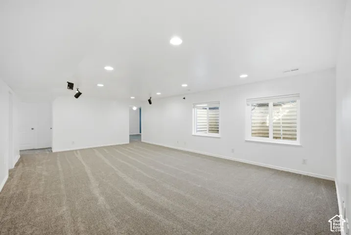 Spacious interior with neutral carpeting, recessed lighting, track lighting, and multiple windows