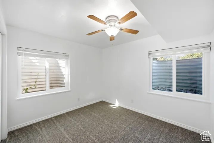Recessed lighting, ceiling fan with light fixture, two windows, and gray carpet flooring