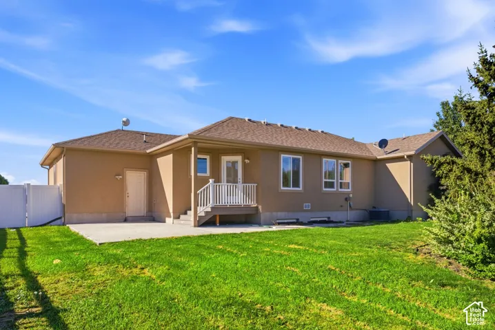 Stucco exterior with a pitched shingle roof, white privacy fence, and concrete patio