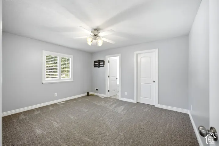 Recessed window with white blinds, neutral gray wall tones, ceiling fan with integrated lighting, and a paneled interior door
