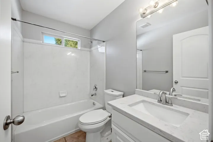 Bathtub with white surround and chrome fixtures, privacy window, white vanity with integrated sink, white countertop, and brushed nickel faucet