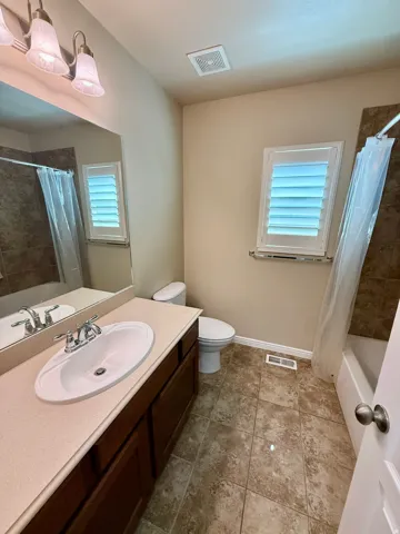 Bathroom 2- Vanity with an integrated sink, wood-finish cabinetry, and a light-toned countertop
