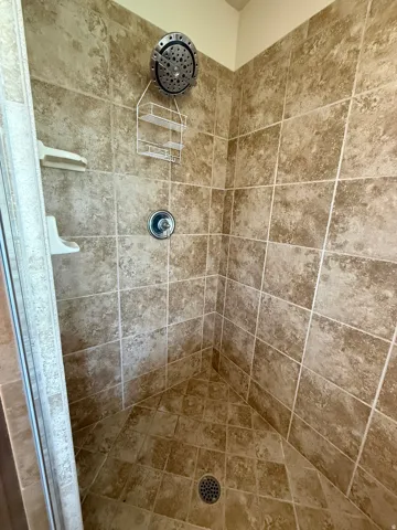 Master Bathroom  tiled shower enclosure with a stainless steel rainfall shower head and chrome fixtures