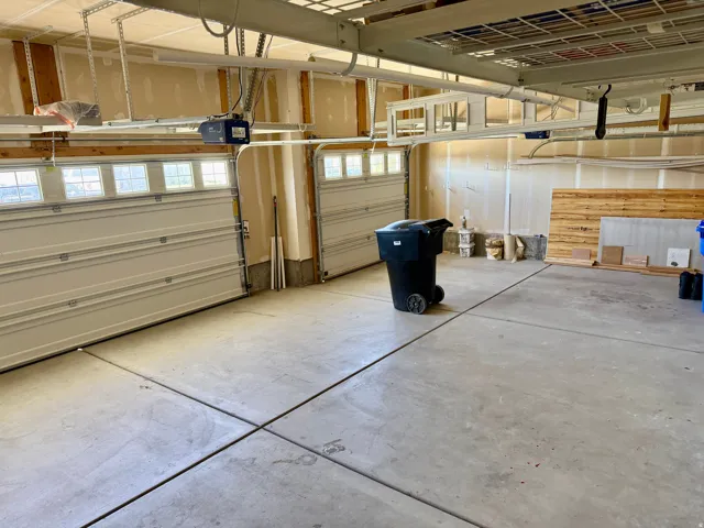 Three-car garage featuring a concrete floor, overhead storage racks, and two garage doors with upper window inserts for natural light