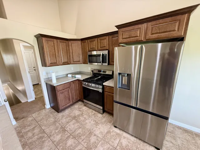 Kitchen featuring wood-finish cabinetry, stainless steel appliances, and tile flooring
