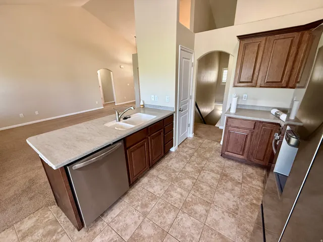Kitchen peninsula  with an undermount sink, stainless steel dishwasher, and wood cabinetry