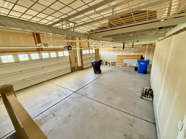 three-car garage featuring a concrete floor, overhead storage racks, and two garage doors with upper window inserts for natural light