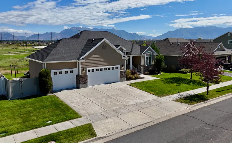 Exterior featuring a multi-car driveway, Three-car garage, established front yard landscaping, and a mountain backdrop