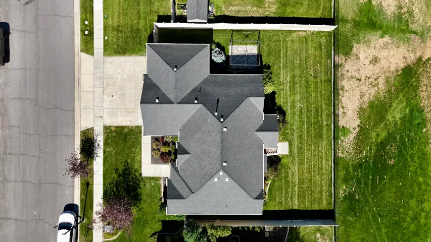 Expansive lot with a pitched shingle roof, established lawn areas, and a concrete driveway