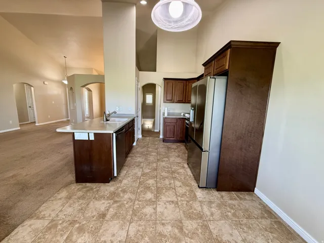 Kitchen featuring a peninsula with sink, tile flooring, dark wood cabinetry, and stainless steel appliances