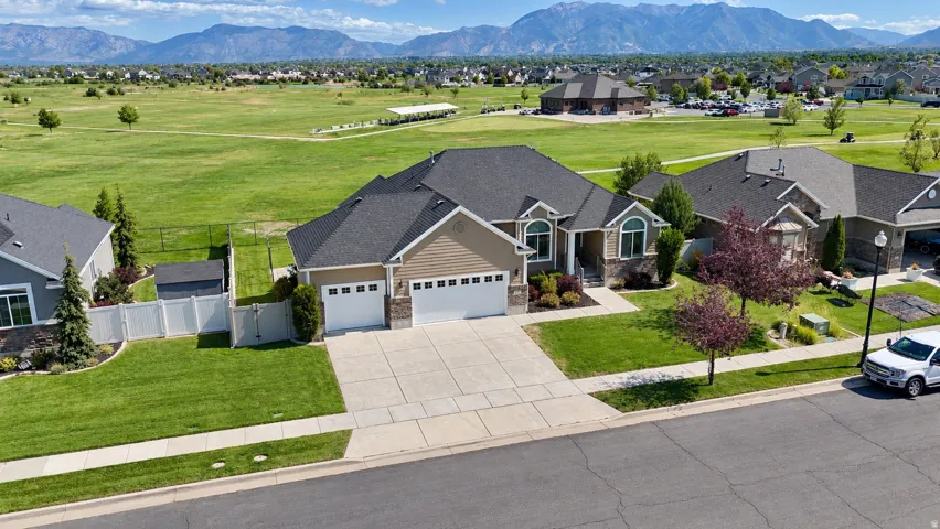 Home that backs up to Cranefield Golf Course- featuring a three-car garage, stone and siding exterior, and a well-maintained yard.