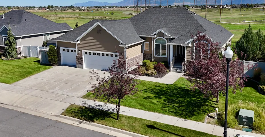 Siding exterior with brick accents, attached three-car garage, mature landscaping, and front entry with arched window