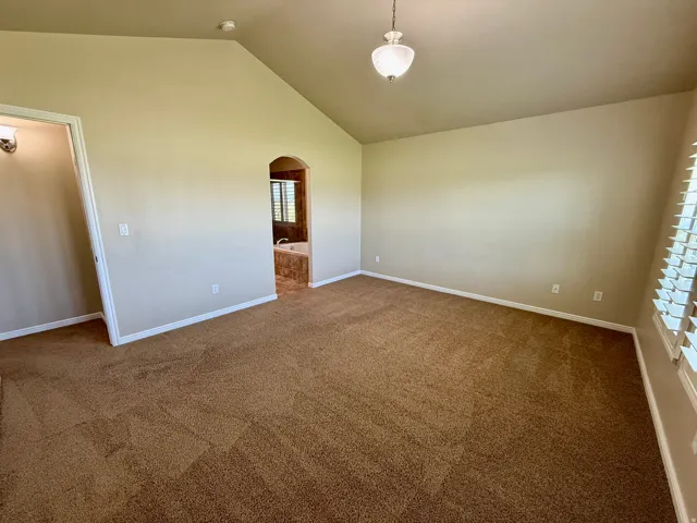 Master Bedroom with vaulted ceilings featuring multiple windows with white plantation shutters, large windows with tons of natural light.