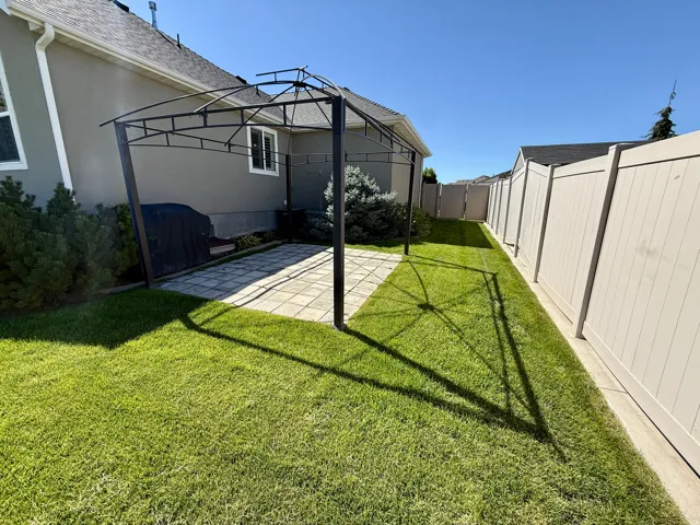 Private backyard featuring a Gazebo paved patio area, green lawn, and full-height privacy fencing