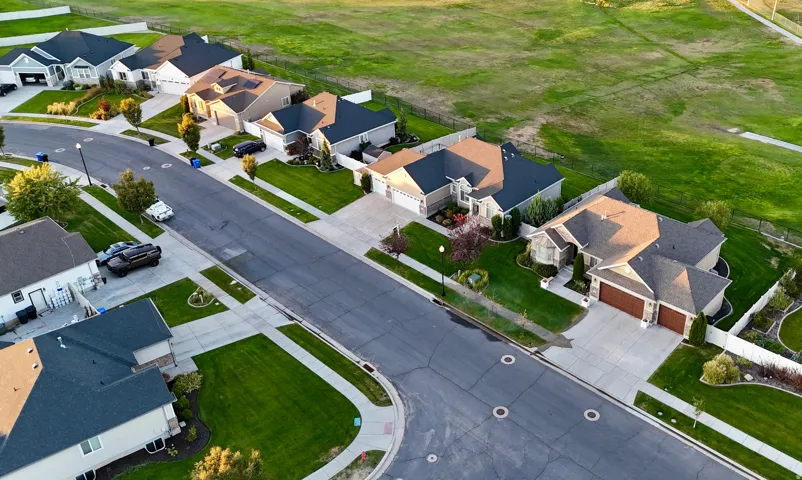 Residential neighborhood with paved streets and sidewalks, featuring landscaped front yards and golf course behind