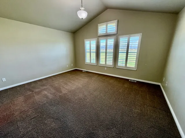 Master Bedroom with vaulted ceilings featuring multiple windows with white plantation shutters, large windows with tons of natural light.