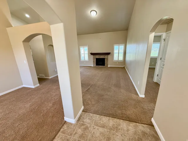 Vaulted ceiling, arched doorways, tiled entryway, built-in fireplace, and plantation shutters
