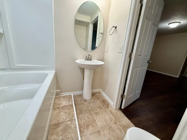 Bathroom 3, Pedestal sink with an oval mirror, tile flooring, and a white bathtub