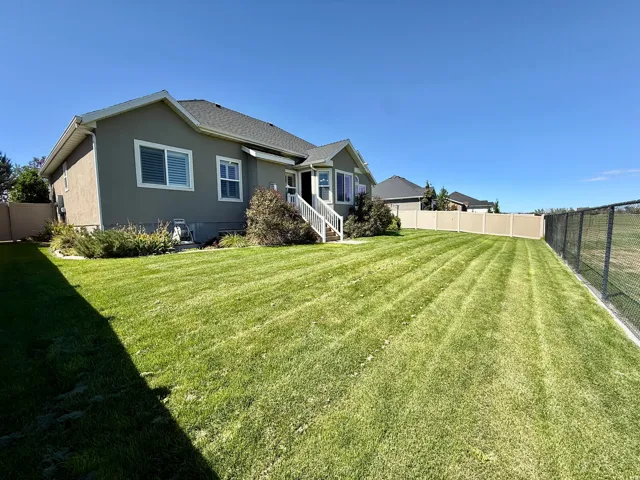 Expansive green lawn with a privacy fence and chain link fence