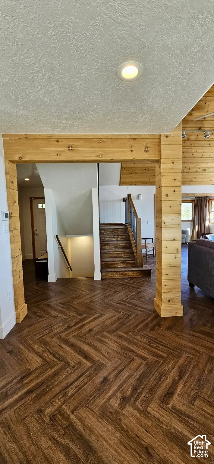 Herringbone wood-finish flooring, wood-clad structural beams, recessed ceiling lighting, and a multi-level staircase with wood treads and metal railing