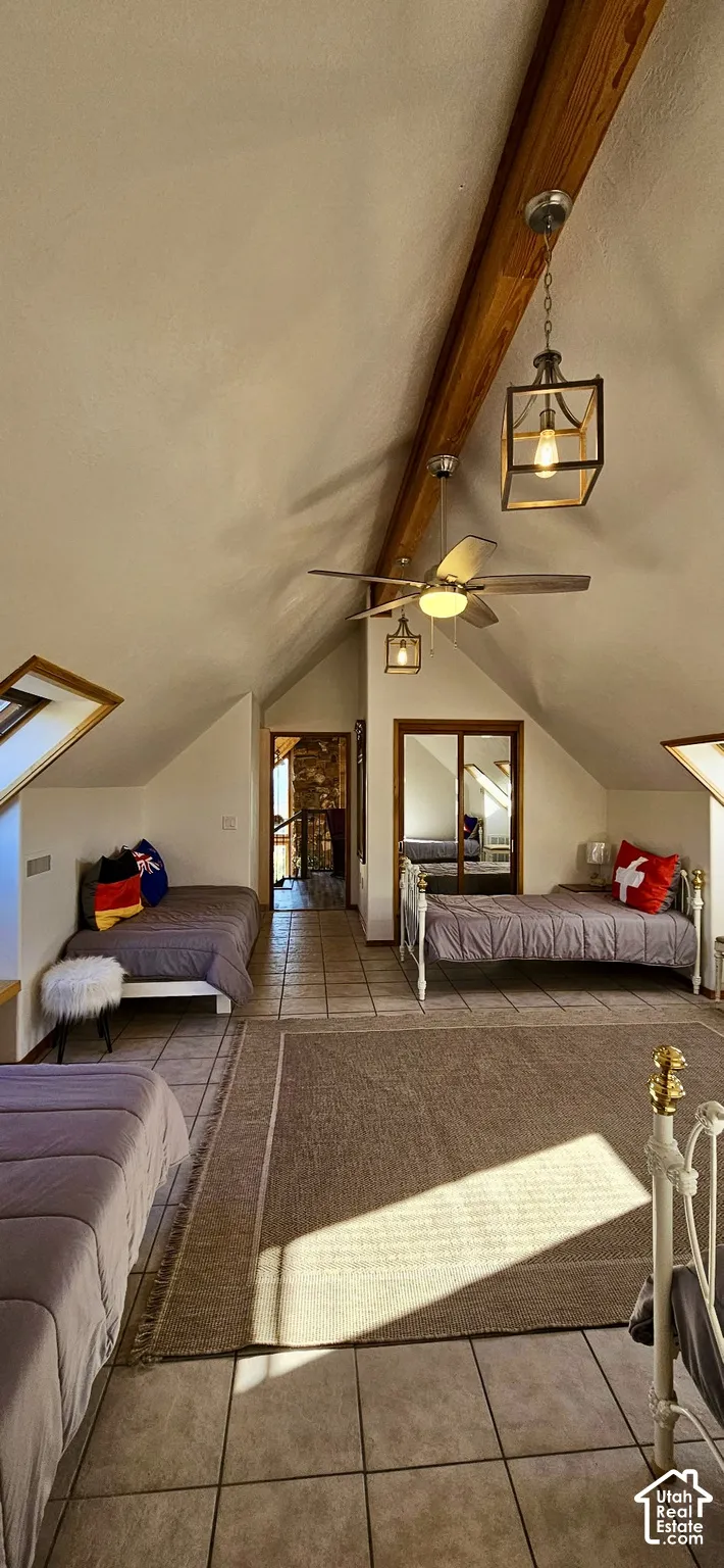 Vaulted ceilings with exposed wood beams, tile flooring, and integrated skylight windows