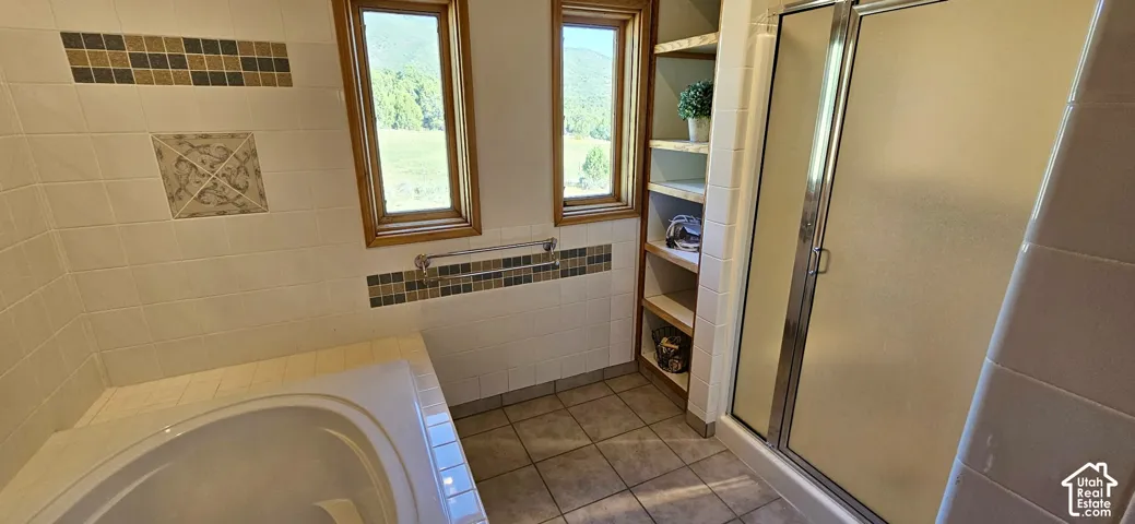 Soaking tub with white tile surround, integrated shelving, and dual windows