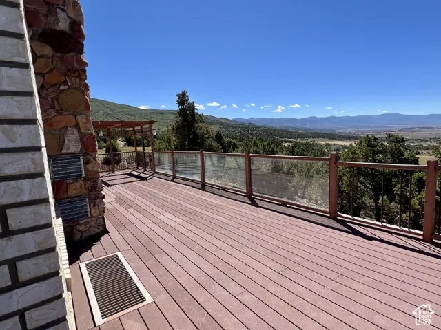 Expansive outdoor deck with composite decking, glass panel railing, and a stone-clad exterior wall