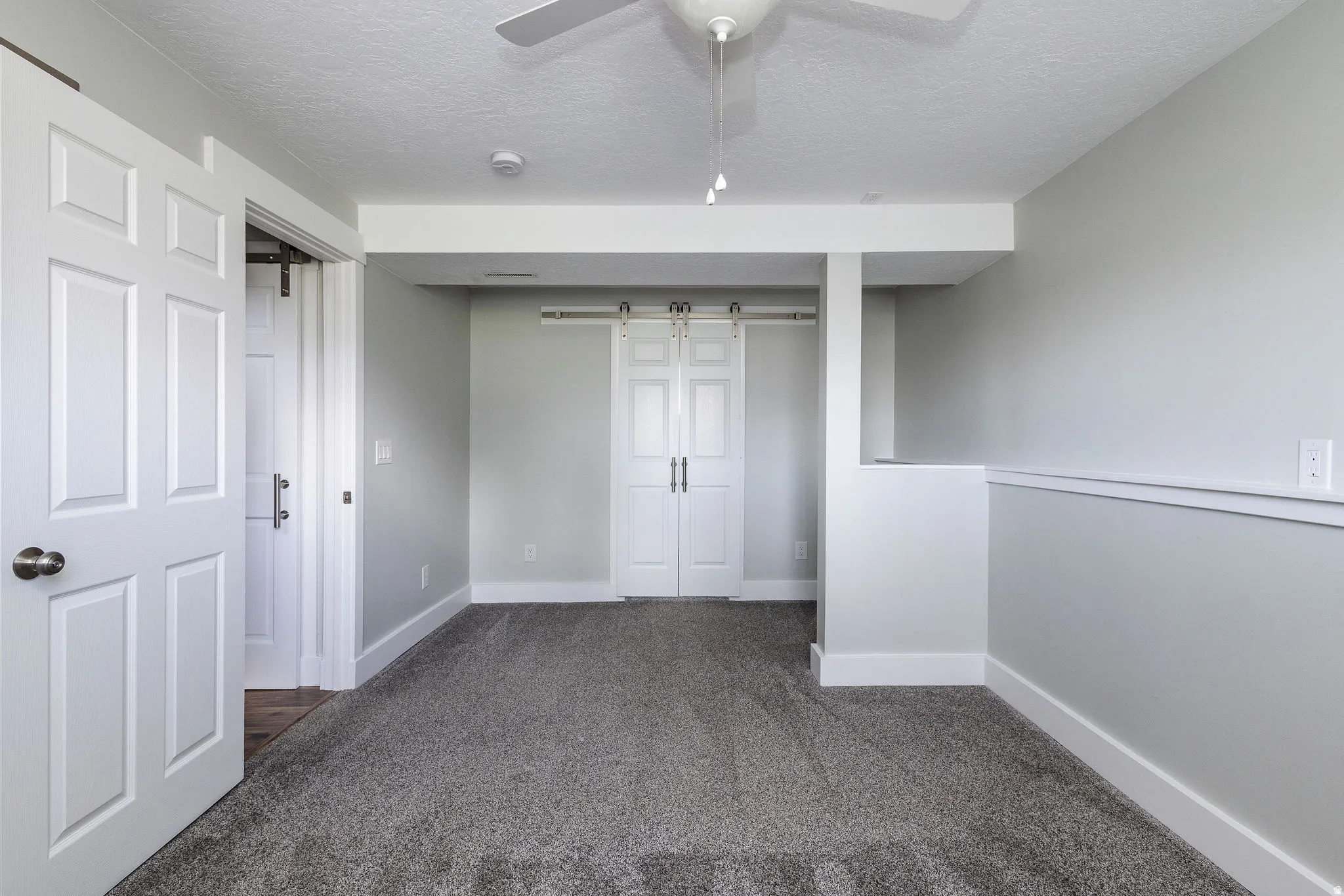Plush gray carpeting, white trim, and a ceiling fan