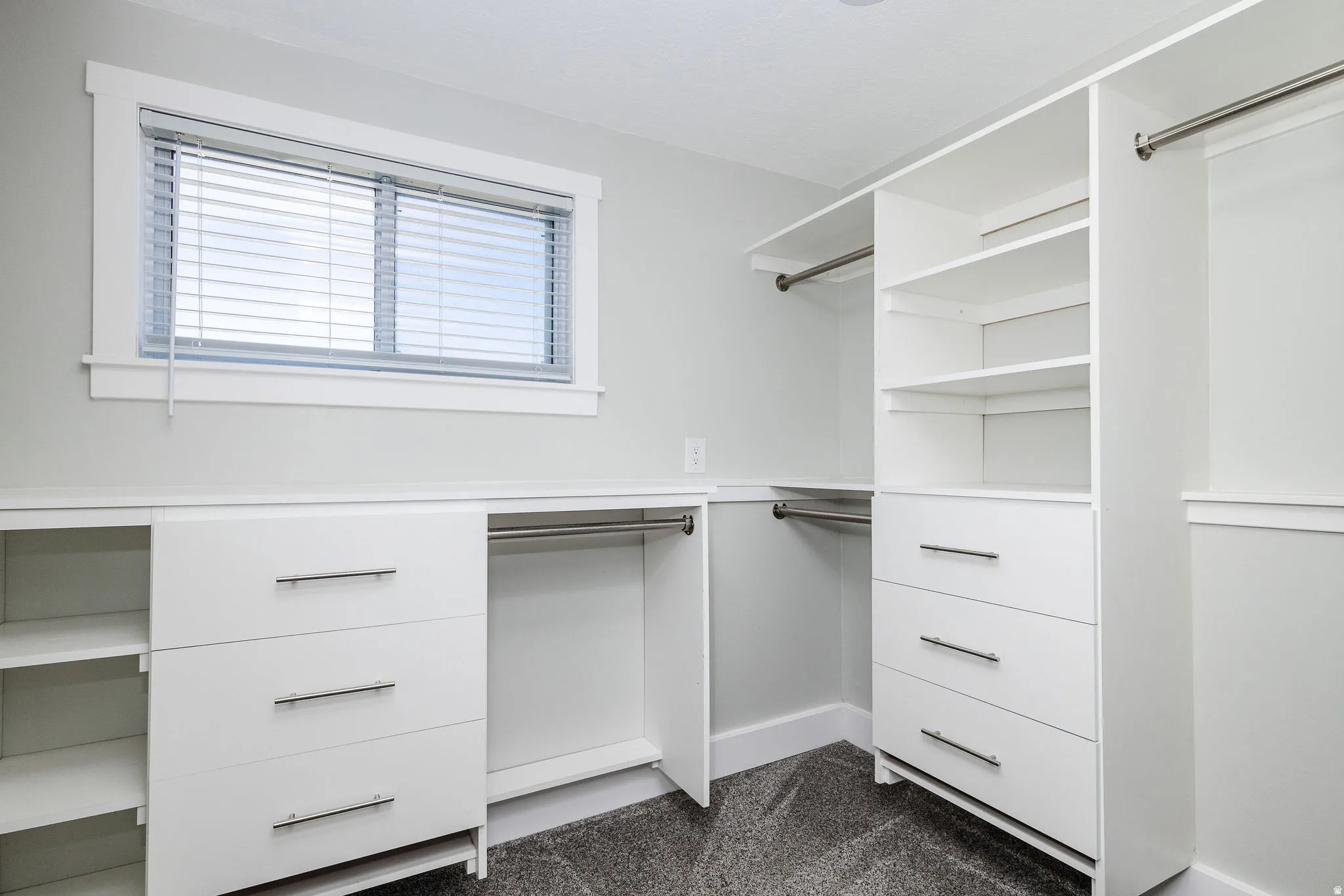 Built-in closet system featuring white cabinetry, multiple drawers with brushed nickel hardware, integrated shelving, and hanging rods