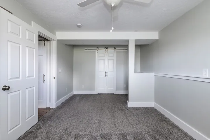 Plush gray carpeting, white trim, and a ceiling fan
