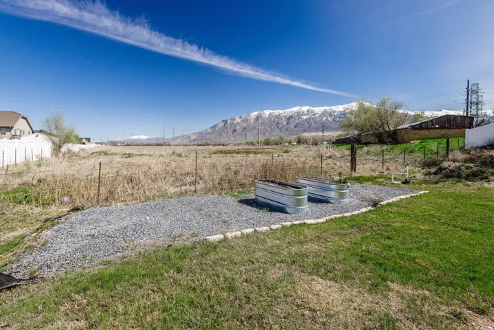 Landscaped area featuring two galvanized metal planters set on a gravel base with concrete block edging, bordered by a grassy lawn