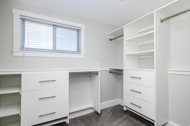 Built-in closet system featuring white cabinetry, multiple drawers with brushed nickel hardware, integrated shelving, and hanging rods