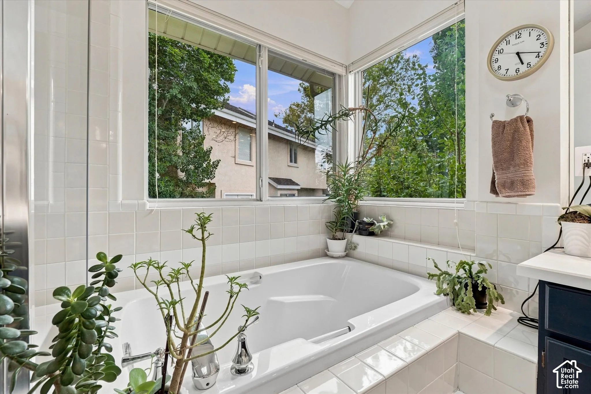 Primary Bath soaking tub with white ceramic tile surround and a corner window