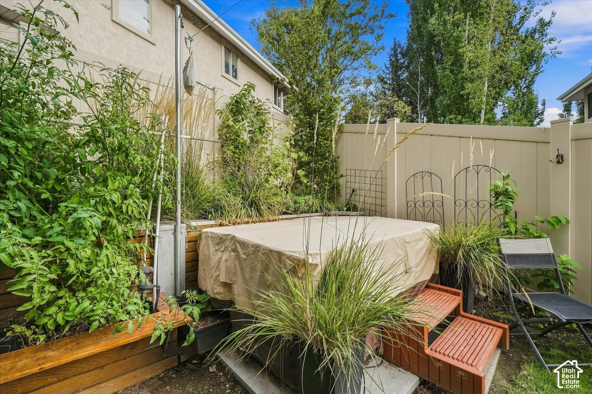 Private backyard area featuring a covered hot tub and raised garden beds