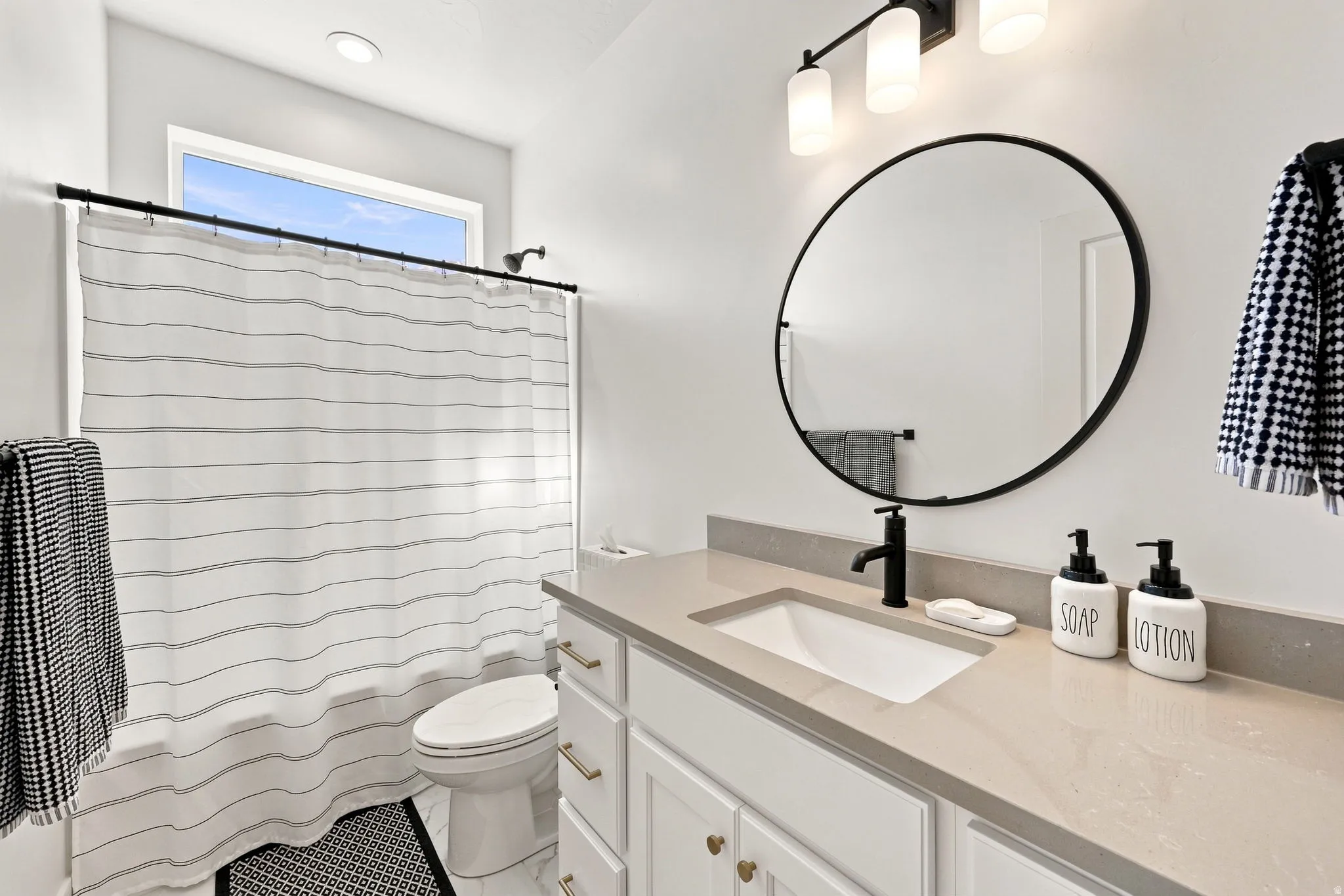 White vanity with gold-tone hardware, undermount sink, and stone-finish countertop