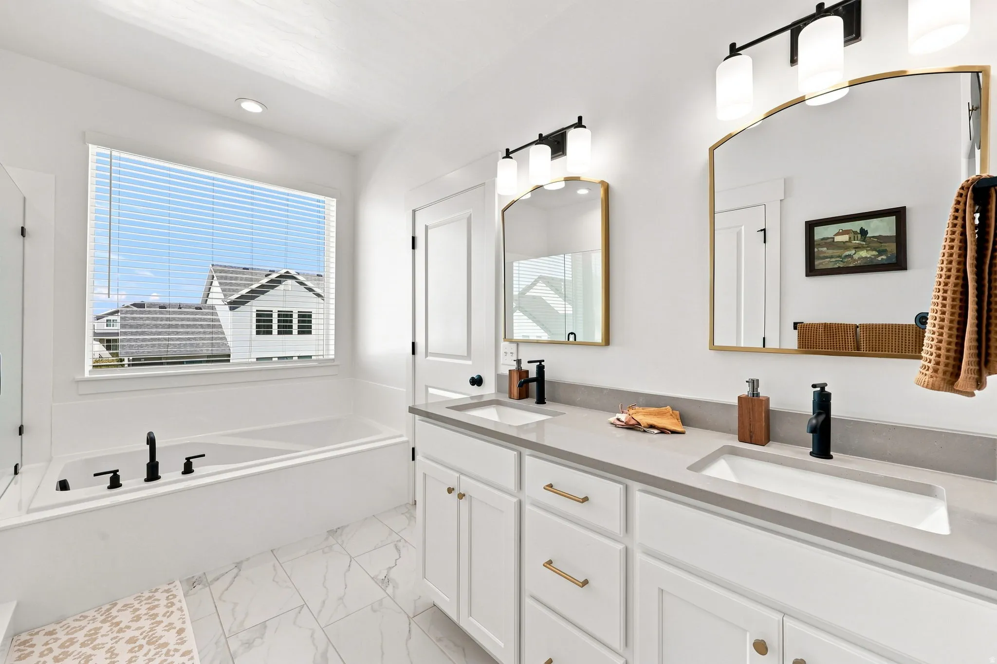 Dual vanity with integrated sinks, light-toned countertop, and gold-framed mirrors
