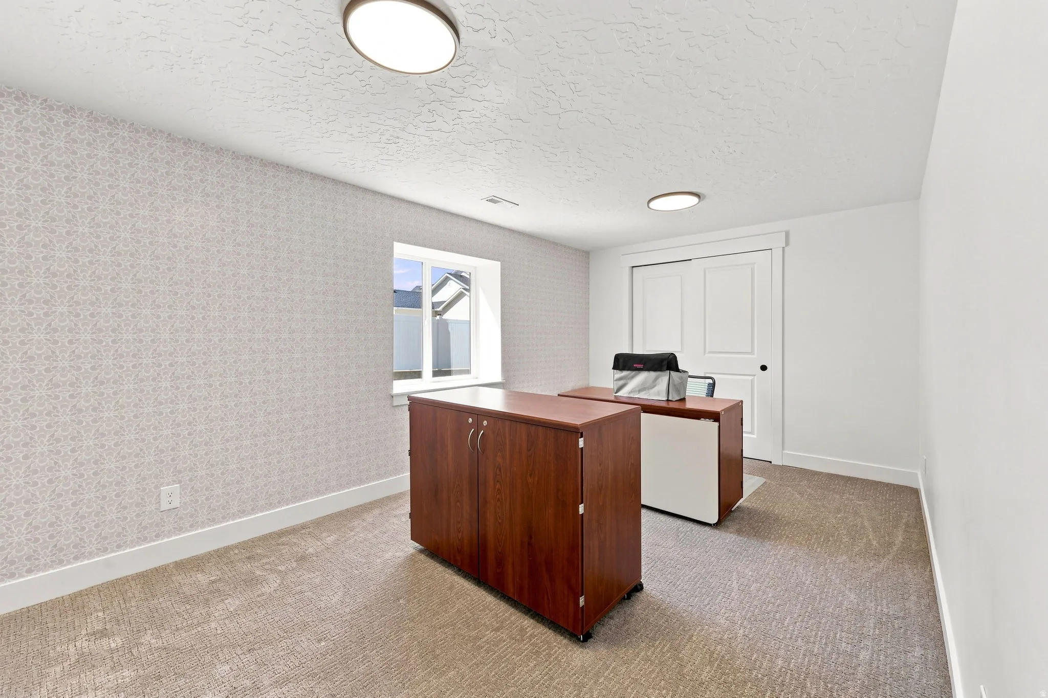 Recessed window, textured accent wall, two flush-mount ceiling lights, light-toned carpeting, and a built-in sliding closet