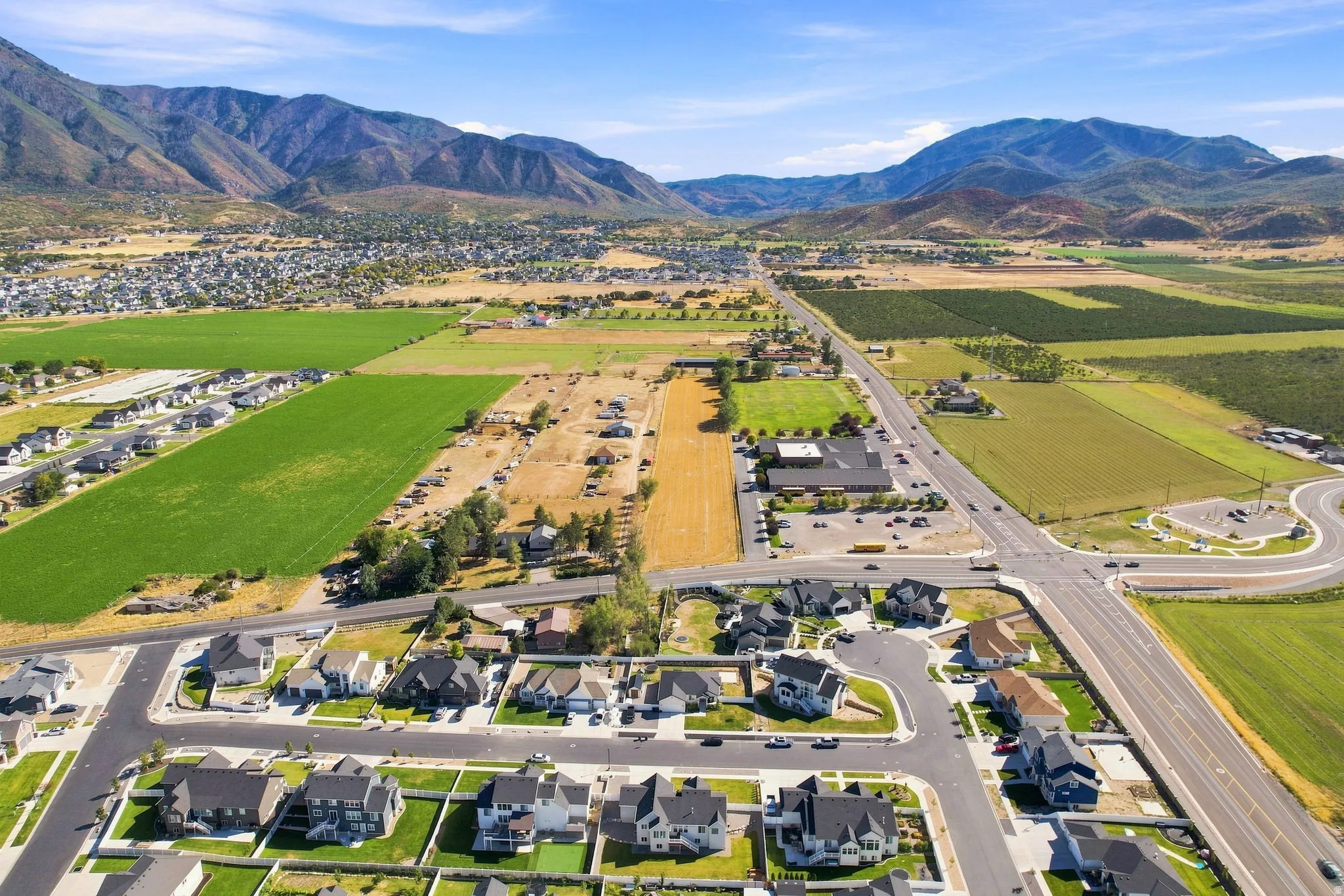 Expansive mountain backdrop with a visible road network, residential developments, and agricultural fields