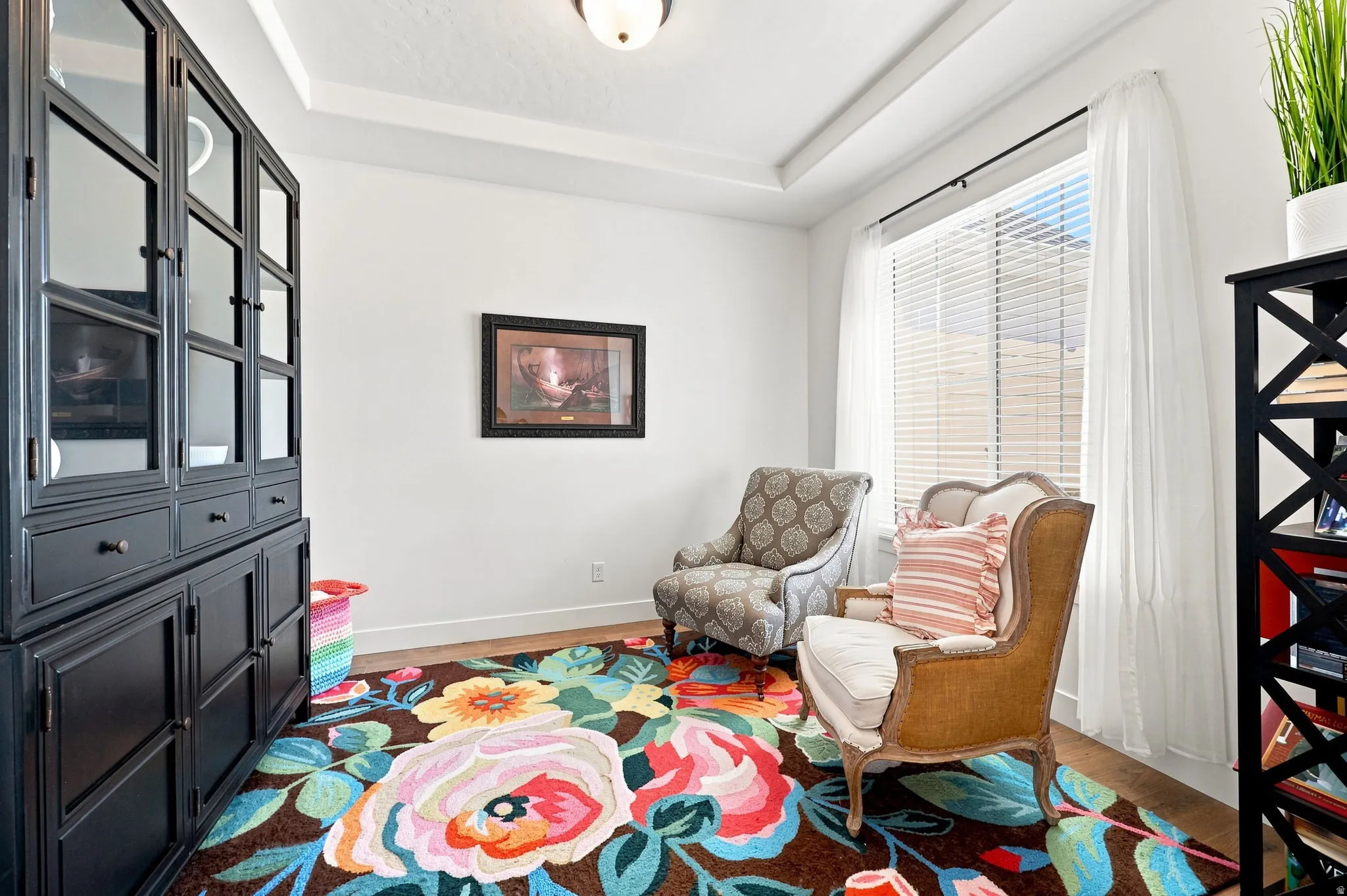 Tray ceiling detail, large window with blinds, wood-finish flooring, and a built-in display cabinet
