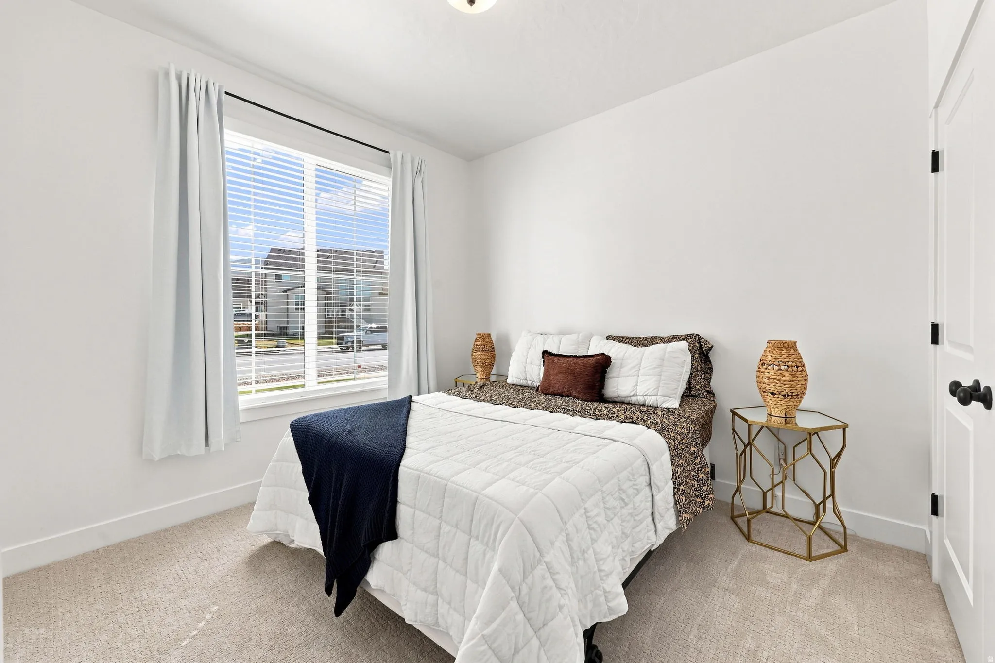 Bright room with a large window, soft carpeting, and a white door with black hardware