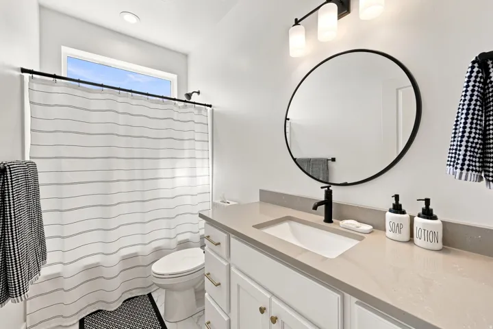 White vanity with gold-tone hardware, undermount sink, and stone-finish countertop