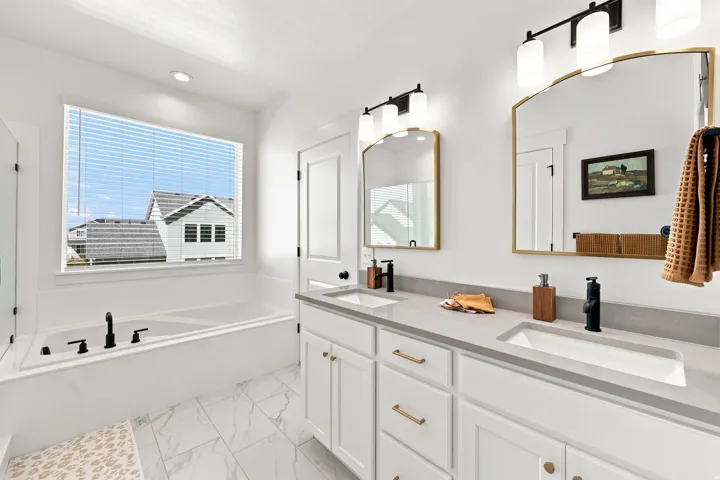 Dual vanity with integrated sinks, light-toned countertop, and gold-framed mirrors