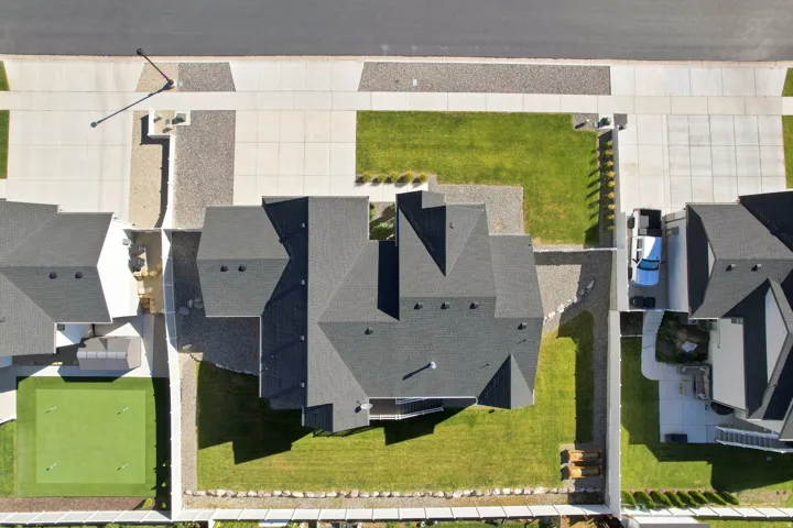 Asphalt shingle roofing, concrete driveway, concrete sidewalk, green lawn, gravel landscaping